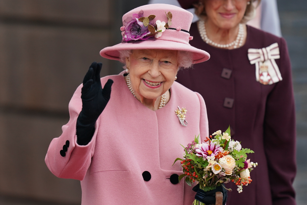 Image of Her Majesty Queen Elizabeth the second wearing a pink coat and hat, and holding a posy of flowers