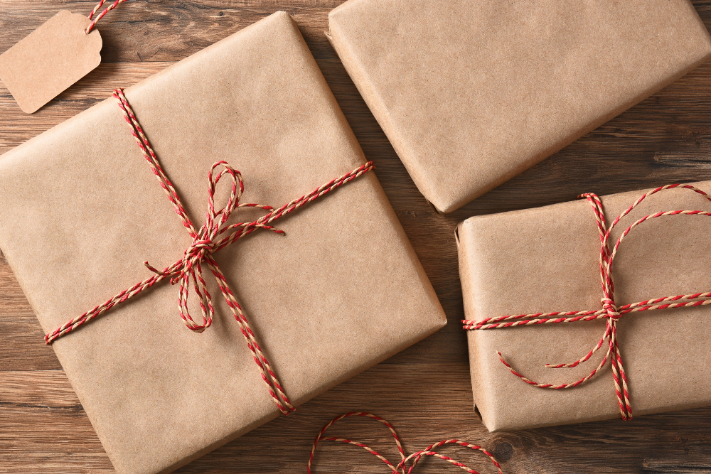 Christmas presents in brown gift wrap and a red and white string bow.